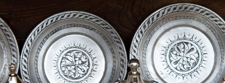 Engraved antique pewter plates on a dark wooden shelf