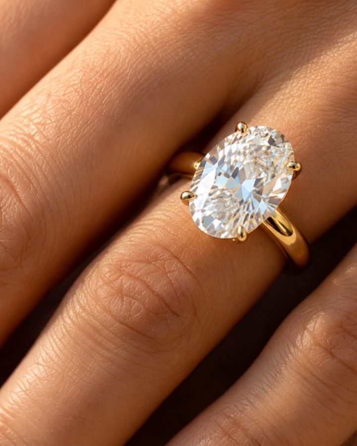 An oval diamond in a yellow-gold mount, worn on the hand